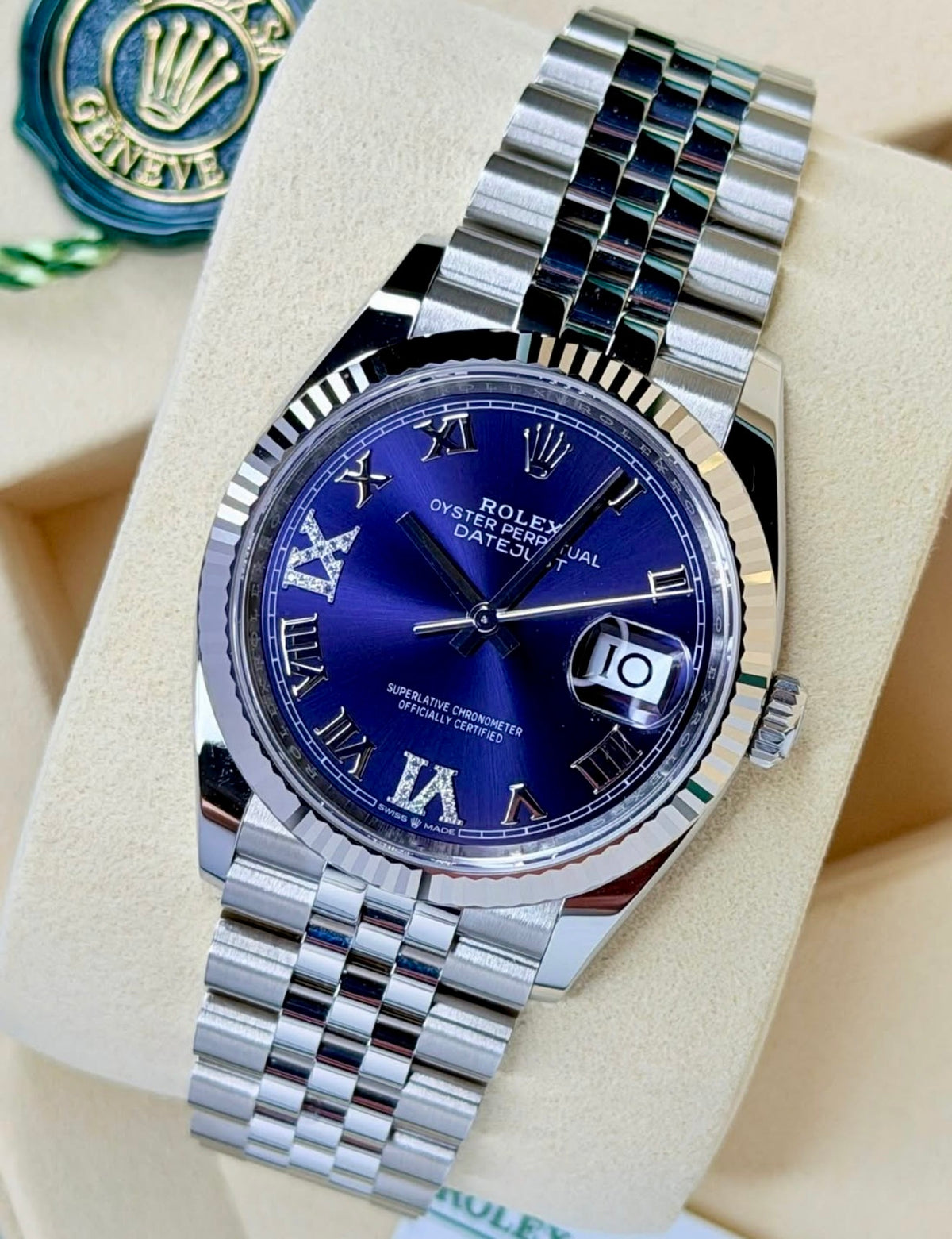Angled view of the Rolex Datejust 36 126234 aubergine dial and Jubilee bracelet beside a green Rolex hangtag.