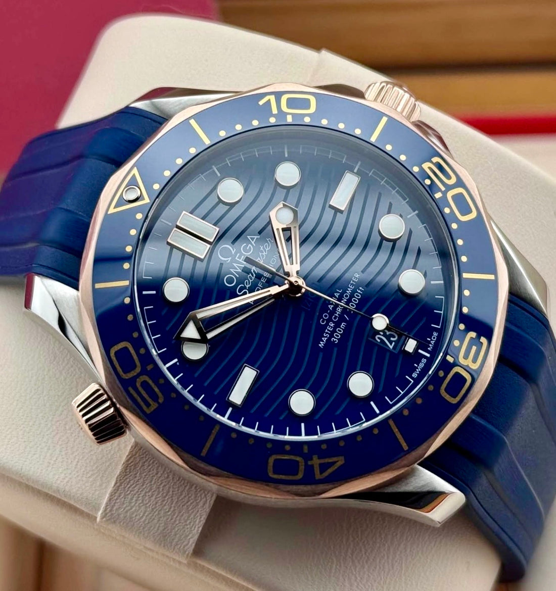 OMEGA Seamaster Diver 300M 210.22.42.20.03.002 — blue wave dial and two-tone bezel, angled front view on blue rubber strap