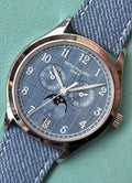 Patek Philippe Annual Calendar Moon Phases 4946G-001 with blue-gray dial, angled front close-up against blue background