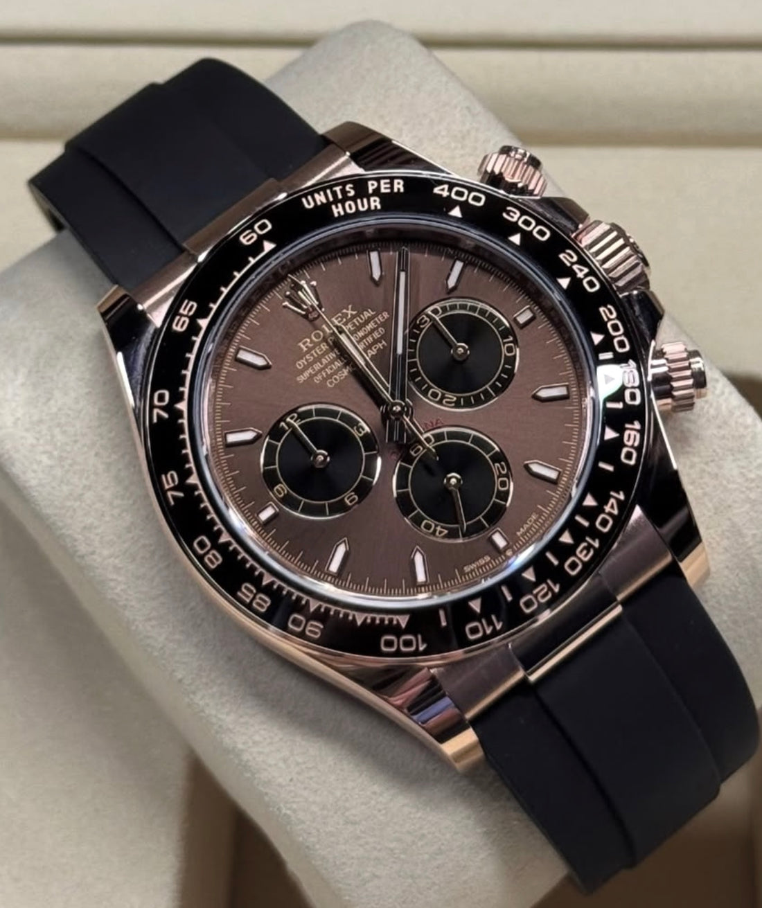 A close-up of a Rolex Daytona watch with a chocolate dial, rose gold case, black cerachrome bezel, and black Oysterflex strap
