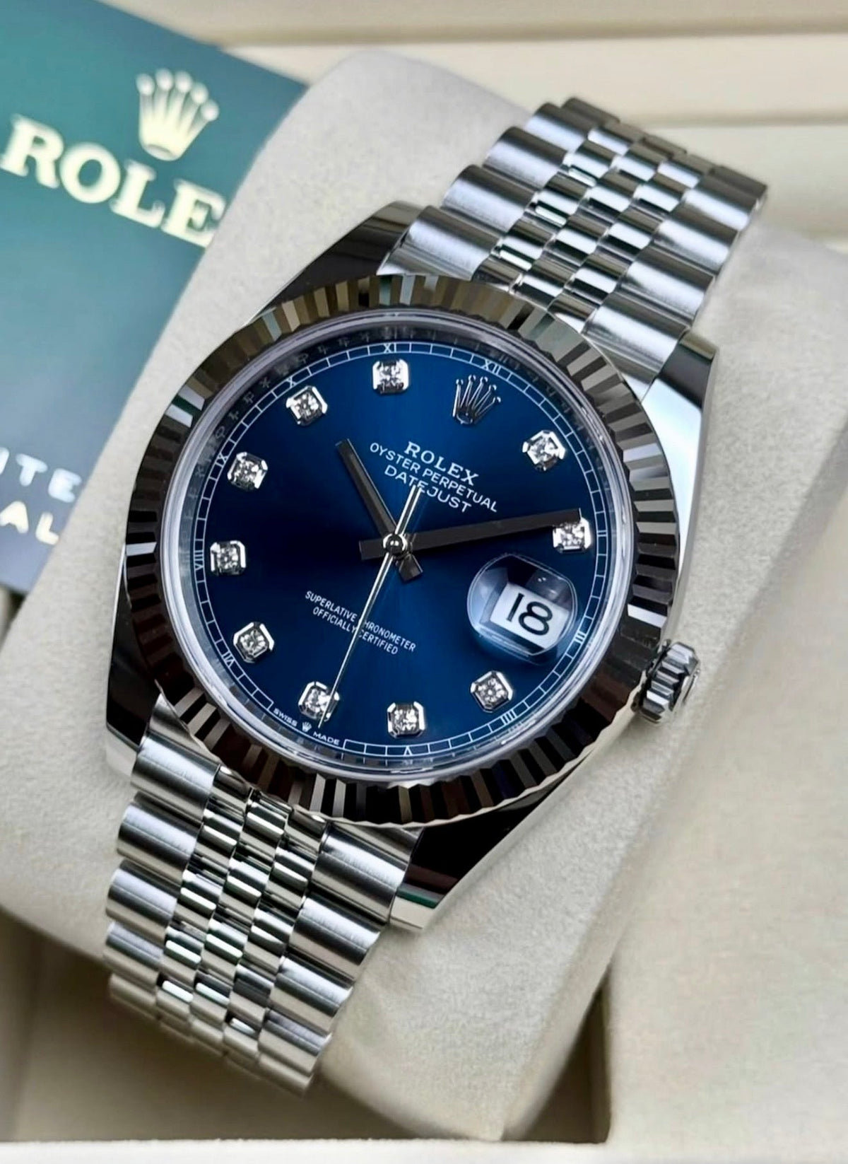 Rolex Datejust 41 126334 opposite diagonal close-up with blue diamond-set dial, fluted bezel and Jubilee bracelet beside Rolex booklet